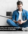 Man sitting near dual USB C and A wall outlet with 4.8A fast charging, 15A 125V, tamper-resistant receptacle and wall plate, 2 pack, black.