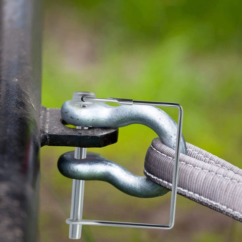 Close-up of Ten Pack 2.75 Inch By 0.25 Inch Trailer Pins For Hitch, locking a gray coupler on farm trailer with green background.