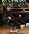 Person relaxing in Ergonomic Gaming Chair With Massage Lumbar, Footrest, And 2D Linkage Armrests, black, in home office setup