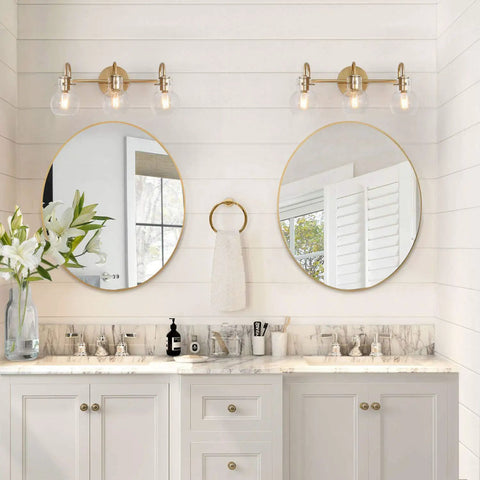 Gold 3 Light Vanity Light Fixture Over Mirror With Globe Clear Glass Shades in chic bathroom setting