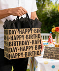 13 Inch Kraft Birthday Gift Bag With Tissue Paper And Greeting Card Black Happy Birthday Lettering Design Perfect For Men Women And Kids Eco Friendly Gift Bag For Any Occasion held by person outdoors near birthday table