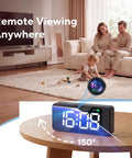 Super Sleek Hidden Camera Clock With 4K Wireless WiFi Surveillance Easy Magnet Mount Setup No Sweat Required And Rock Solid All Day Battery For Big Time Indoor Home Security Monitoring displayed on a table with family in background.