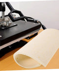Heat Press Mat 14.96 By 11.41 Inches Wear-Resistant Sponge Pad next to a heat press machine, for even pressure and insulation