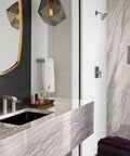 Modern bathroom with marble sink and textured wall, brushed nickel fixtures, mirror, and floral decor