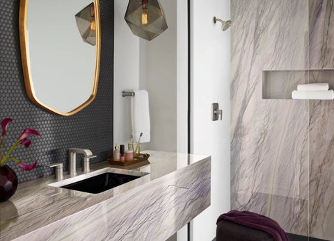 Modern bathroom with marble sink and textured wall, brushed nickel fixtures, mirror, and floral decor