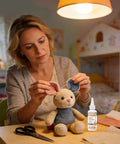 Woman repairing toy with Waterproof Fabric Glue Clear Clothing Adhesive Quick Dry Bonding Solution, bottle on table.
