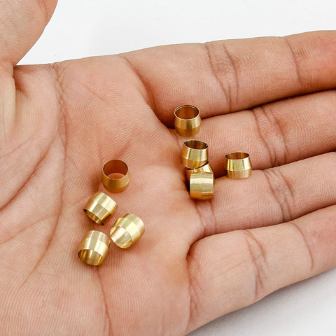 Close-up of brass compression ferrules for 1/4 inch tubing, 50-piece sleeve set held in the palm