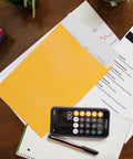 Open End Manila Envelopes 7.5 By 10.5 Inches Yellow 100 Pack With Peel And Seal Closure on a desk with papers and a phone calculator.