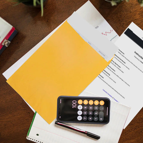 Open End Manila Envelopes 7.5 By 10.5 Inches Yellow 100 Pack With Peel And Seal Closure on a desk with papers and a phone calculator.