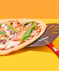 Pizza peel, 9-inch perforated aluminum with red handle, TKC branding, angled view under a veggie pizza.