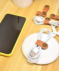 Leather Cord Organizer And Cable Keeper Case for Earbuds and Headphones on desk with phone and cables