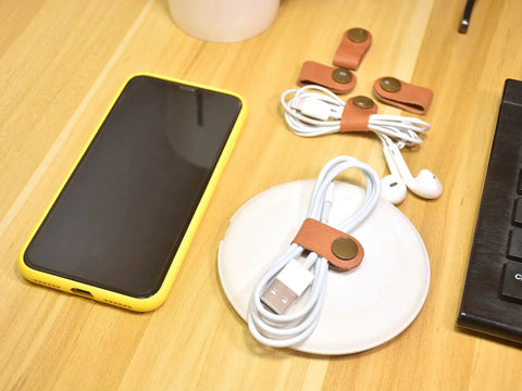 Leather Cord Organizer And Cable Keeper Case for Earbuds and Headphones on desk with phone and cables