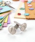Top Tier 100 Pack 8mm Slotted Phillips Head Screw Brads In Sleek Silver on a crafting table with colorful paper, buttons, and scissors.