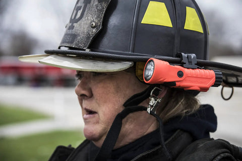 Firefighter wearing helmet with Firefighter LED Helmet Light With 180 Degree Articulating Head And Dual Beam Output, Orange
