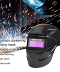 Sun Powered Auto Darkening Welding Helmet With LCD View next to electric welding sparks.