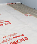 Top Shelf 100 Square Foot Laminate And Engineered Wood Flooring Underlayment Roll laid on floor with grey walls.