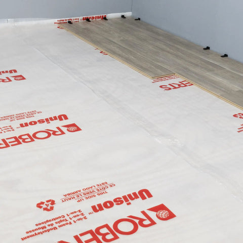 Top Shelf 100 Square Foot Laminate And Engineered Wood Flooring Underlayment Roll laid on floor with grey walls.