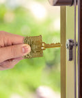 Brass House Key with ADA Friendly Large Head for easy grip, shown entering a lock, engraved home design visible