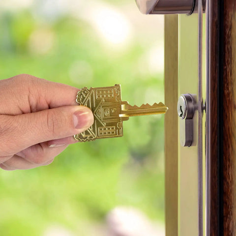 Brass House Key with ADA Friendly Large Head for easy grip, shown entering a lock, engraved home design visible