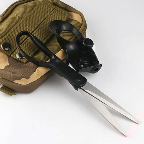 Side view of laser-guided sewing scissors with ergonomic black handle and long silver blades beside a tan tactical pouch.