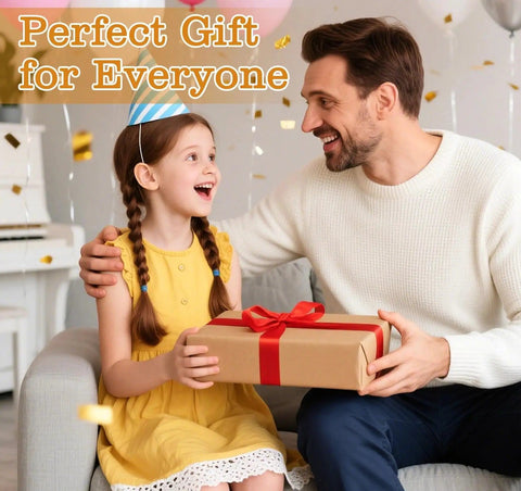 Child in yellow dress and party hat receiving a gift from an adult man in a white sweater, both smiling, in a festive setting.