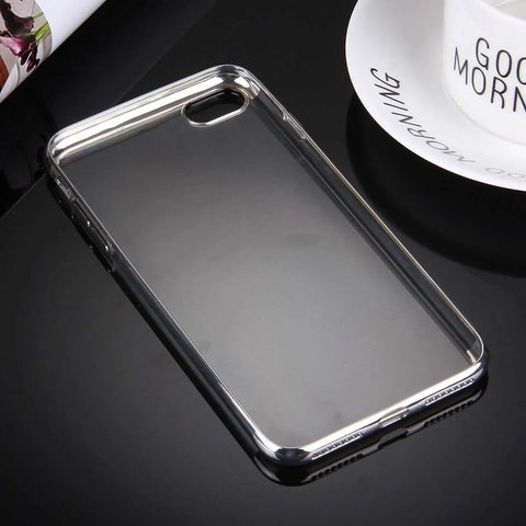 Transparent phone case with silver edges on black reflective surface near 'Good Morning' mug