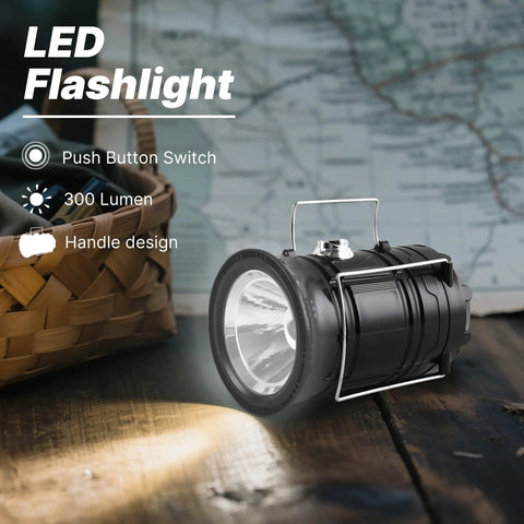 Collapsible Solar Camping Lantern With USB Rechargeable LED Flashlight on a wooden surface, handle visible, emits light