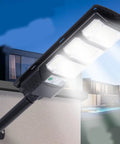 JUDYSSY 400W Super Bright Led Beads Commercial Solar Flood Lights mounted on a wall illuminating a courtyard.