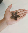 Four Pack Two Point Four Inch Antique Brass Flower Cabinet Knobs With Vintage Floral Drawer Pulls shown in palm