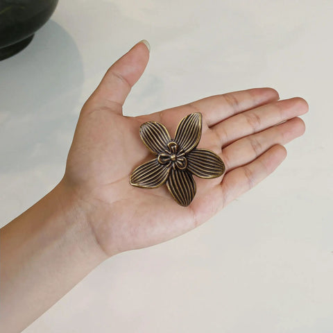 Four Pack Two Point Four Inch Antique Brass Flower Cabinet Knobs With Vintage Floral Drawer Pulls shown in palm