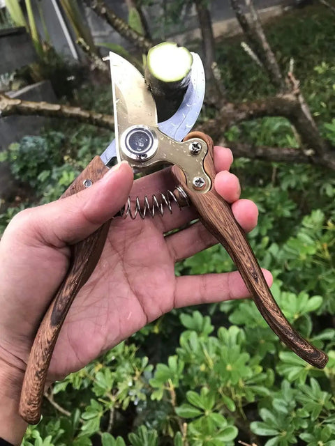 Heavy Duty Garden Pruning Shears With Japanese SK4 High Carbon Steel Blade in hand, wood grain handle, cutting a branch