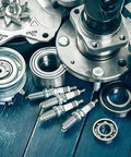 Assorted metal mechanical parts and spark plugs on a wooden surface, suitable for use with Industrial Strength Penetrating Grease Lubricant Aerosol 13 Oz with Extension Tube for Tight Areas Heavy Duty Long Lasting Lubrication Penetrates Metal Parts and Machinery.