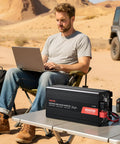 Man using laptop outdoors with Beefy 4000W Power Inverter Converts 12V DC To 120V AC Modified Sine Wave for RV setup on table.