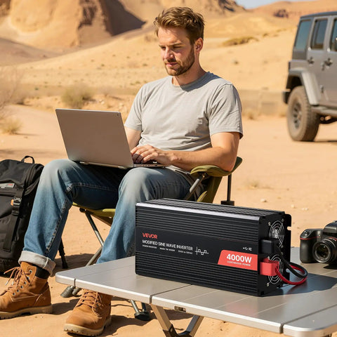 Man using laptop outdoors with Beefy 4000W Power Inverter Converts 12V DC To 120V AC Modified Sine Wave for RV setup on table.
