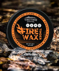 Waterproof Tinder Fire Wax For Wet Wood And Emergency Kits 60g Tin resting on rocks by a stream, packaging visible