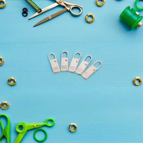 Top Shelf Universal Replacement Zipper Pull Heads 20 Piece Metal Kit on blue surface with scissors and various materials.