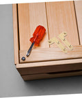 Wooden surface with mounted brass hinge, screwdriver, and screw visible