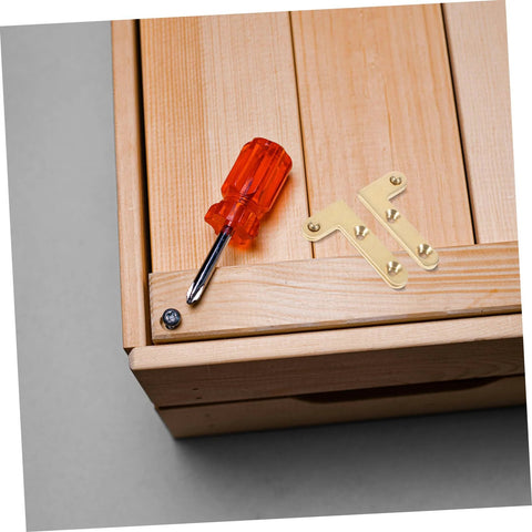 Wooden surface with mounted brass hinge, screwdriver, and screw visible