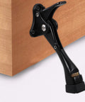 Kickdown Door Stopper With Zinc Alloy Build Low Profile Door Holder attached to wooden surface