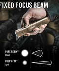 Hand holding Slayer 1150 Lumen USB C Rechargeable LED Flashlight with flat Dune finish, illustrating dual spot and flood beams.