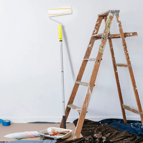 Kickass Detachable Microfiber Paint Roller Brush With Extended Telescopic Handle next to a ladder and paint supplies.