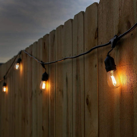 24 Pack LED S14 Replacement Bulbs For Outdoor String Lights Waterproof Shatterproof 1W E26 Medium Base glowing on a fence