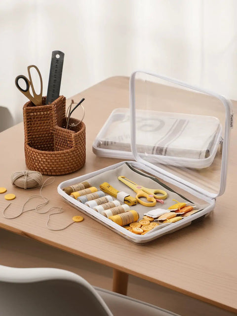 3 Pack Large Clear Hard Shell Zippered Organizer Case Set used for storing sewing supplies on a table next to a woven basket.