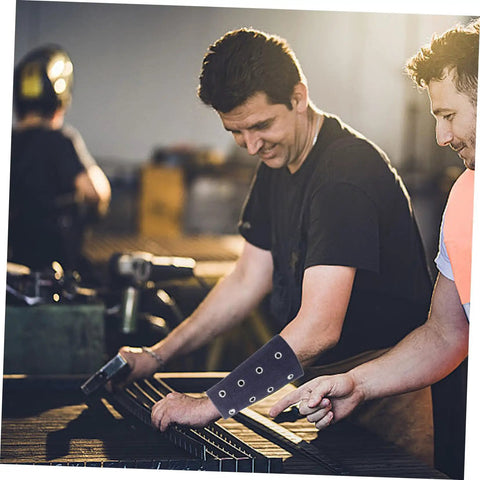 Two men working in a workshop wearing Grab These Heavy Duty Cut Resistant Wrist Sleeves For Men And Women, Featuring Breathable Arm Guards For Gardening, Mechanic Repair, And Industrial Tasks With A Slick Comfy Fit And Rock Solid Protection.