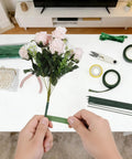 Hands wrapping flowers with tape from Dope DIY Floral Craft Kit With ABS Pearls, Metal Wire, 2mm Flower Stems, Scissors, Pliers