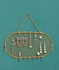 Wall Mounted Jewelry Organizer With Grid Design For Earrings Necklaces Bracelets And Watches In A Dope Sleek Iron Gold Finish Display Rack 35x18cm Durable Earring Holder And Necklace Hanger For Home Decor with jewelry displayed on a green wall