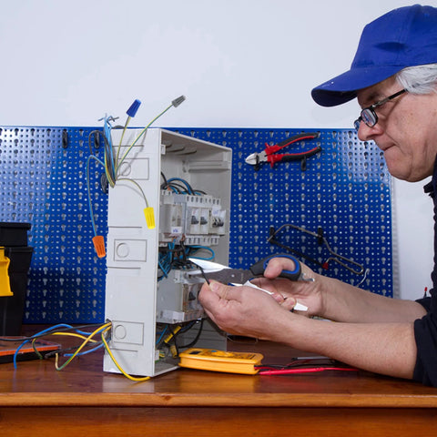 Side view of a technician wiring an open electrical panel with colorful insulated wire connectors (180 pcs) and tools nearby