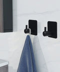 Heavy Duty Adhesive Aluminum Hooks, 12 Pack Black Wall Mount Hooks For Hanging Coats, Hats, Towels, Robes, Keys, And Clothes, Ideal For Kitchen, Bathroom, Home Or Office, Easy Install And Strong Hold holding a towel on a white wall