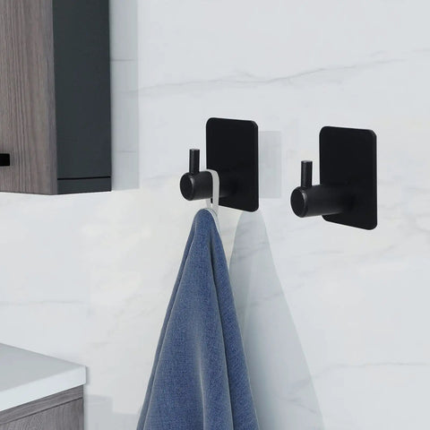 Heavy Duty Adhesive Aluminum Hooks, 12 Pack Black Wall Mount Hooks For Hanging Coats, Hats, Towels, Robes, Keys, And Clothes, Ideal For Kitchen, Bathroom, Home Or Office, Easy Install And Strong Hold holding a towel on a white wall