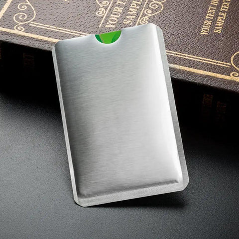 Silver RFID Blocking Sleeve Anti Theft For 4 Credit Cards And 2 Passports Wallet Pocket on a black surface near a book